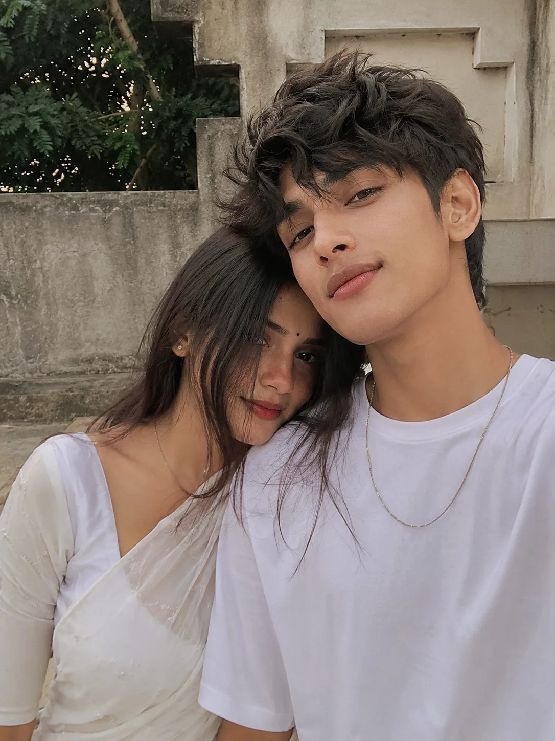 Create a highly realistic, natural smartphone selfie of a beautiful young Indian couple sitting very close together.