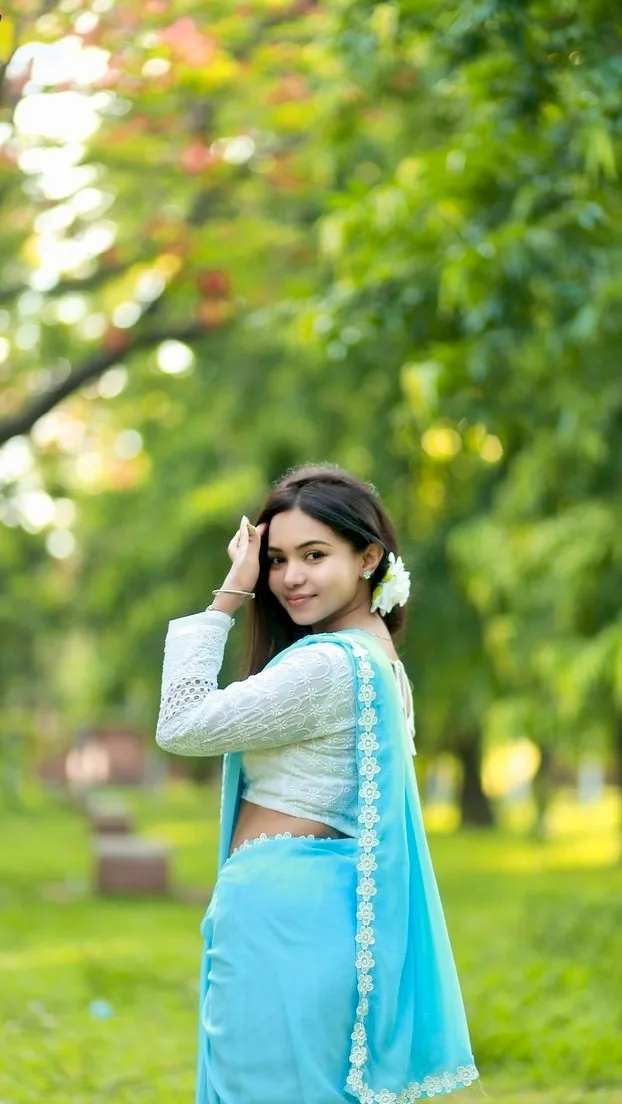 A photorealistic vertical portrait of the young South Asian woman from the reference image, faithfully preserving her exact recognizable