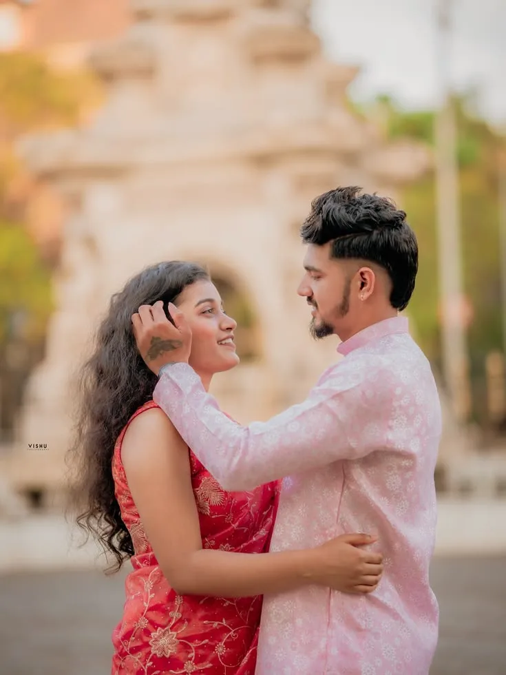 A photorealistic vertical medium-full shot in 3:4 aspect ratio capturing the young South Asian couple from the reference images standing