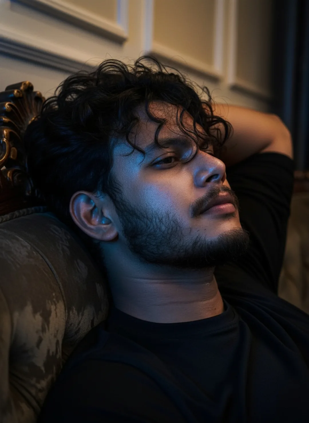 A cinematic close-up portrait of a young South Asian man with thick, messy curly black hair, soft beard and mustache, sharp jawline and