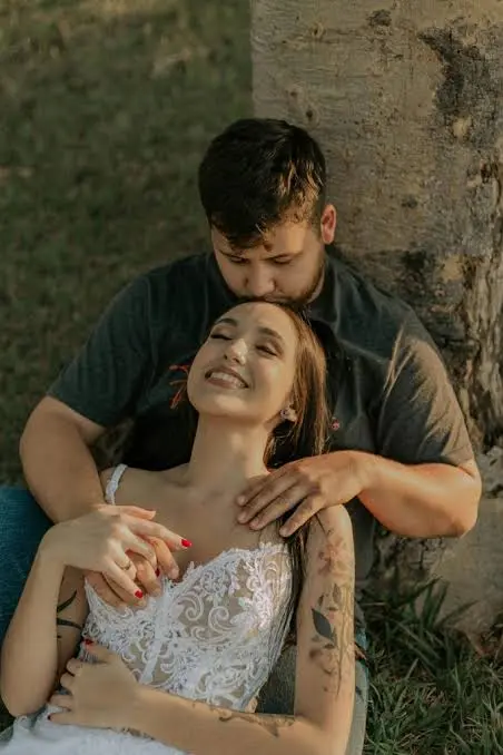Prompt: > Ultra-realistic cinematic outdoor couple portrait, a young adult man sitting closely behind a young adult woman beside a large