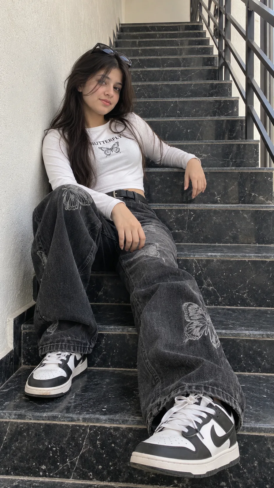 A casually posed photograph of the woman, now seated comfortably on the dark marble steps.