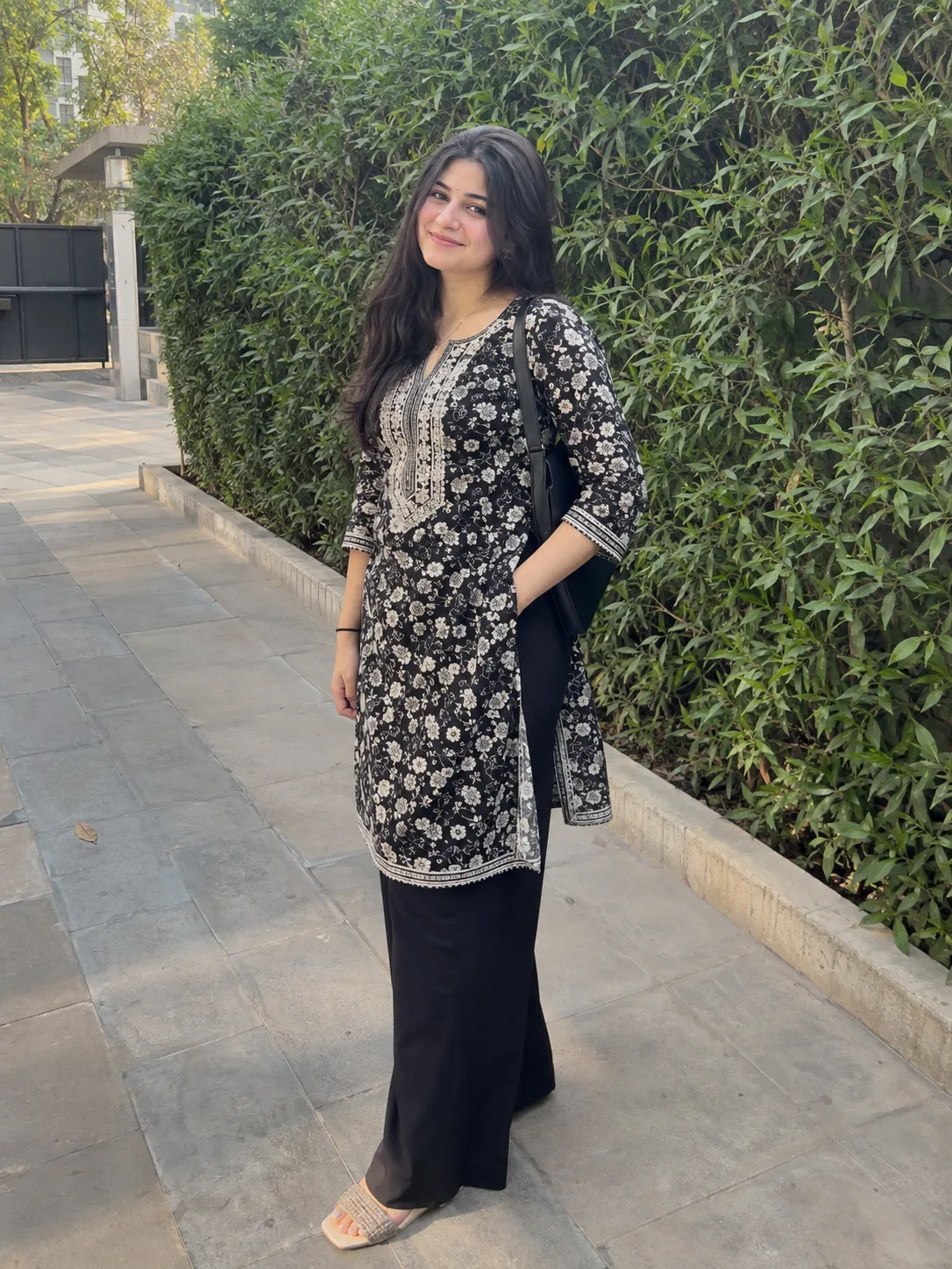 Prompt: A realistic iPhone candid shot of a beautiful 20-year-old Indian woman in a black-and-white patterned kurti and black wide-leg