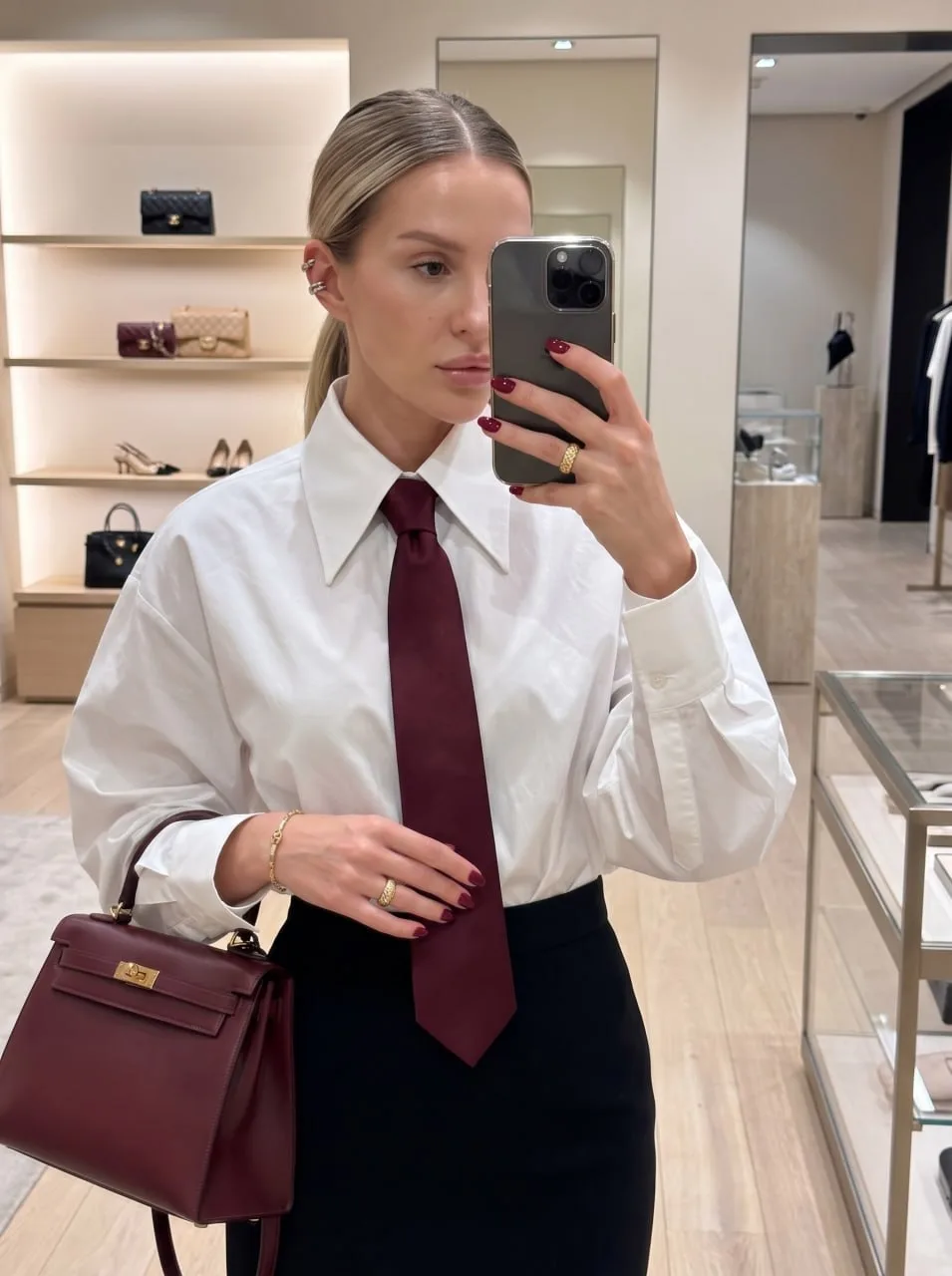 Ultra-realistic candid luxury fashion mirror selfie of a stylish woman inside an elegant designer boutique, photographed from the waist up.
