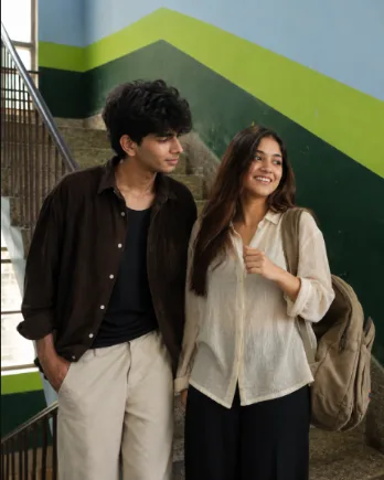A highly realistic, documentary-style photograph of a young couple on an indoor staircase, looking natural and unposed.