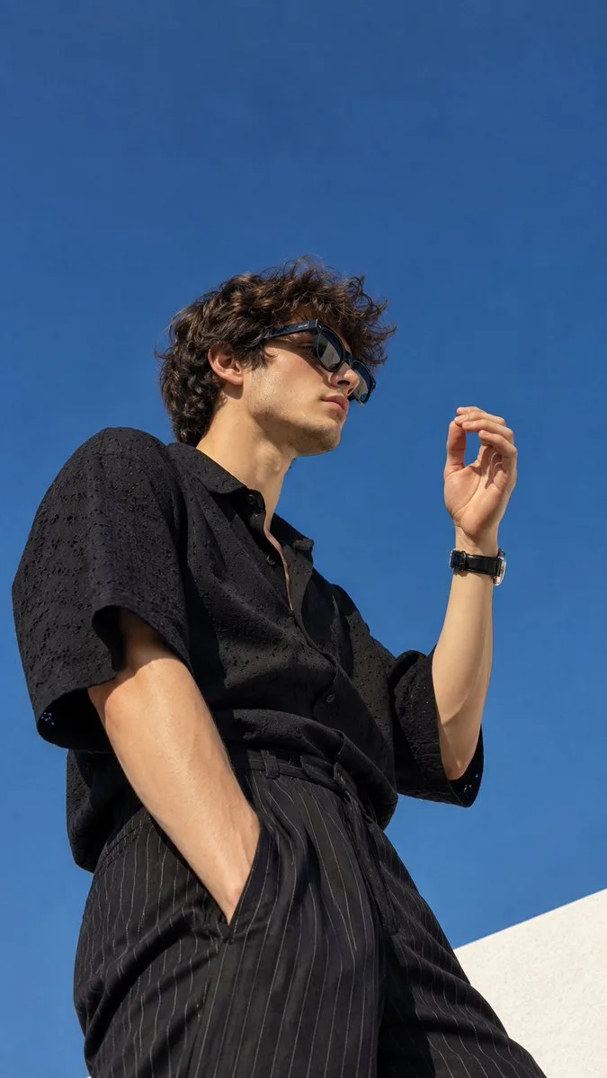 Create an ultra-realistic cinematic fashion editorial photograph of a young man captured from a dramatic low-angle perspective against a