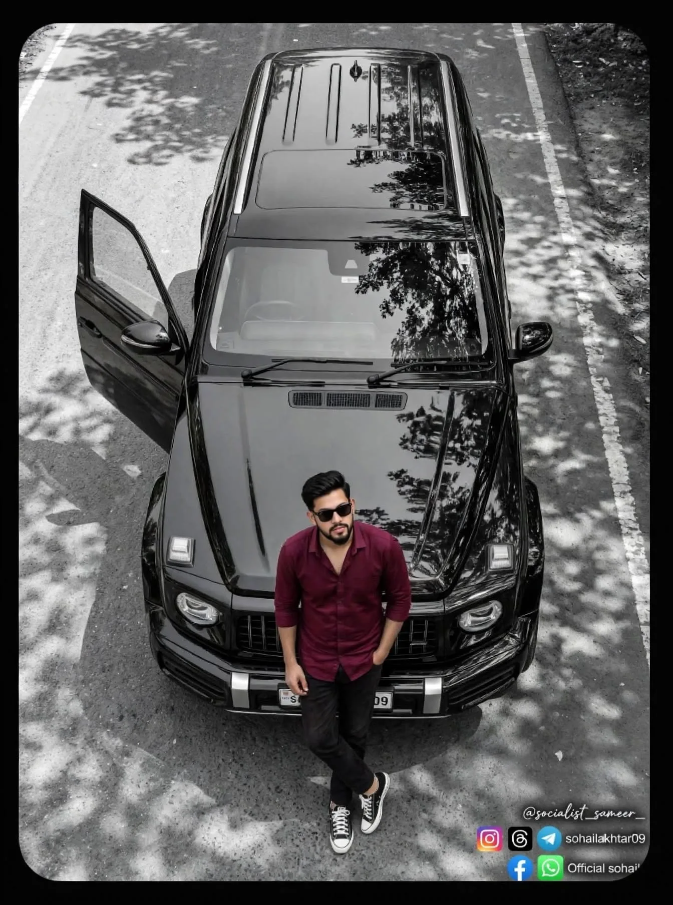 Top-down aerial drone view of a young Indian man with black styled hair, trimmed beard, wearing black sunglasses, maroon button-up shirt,