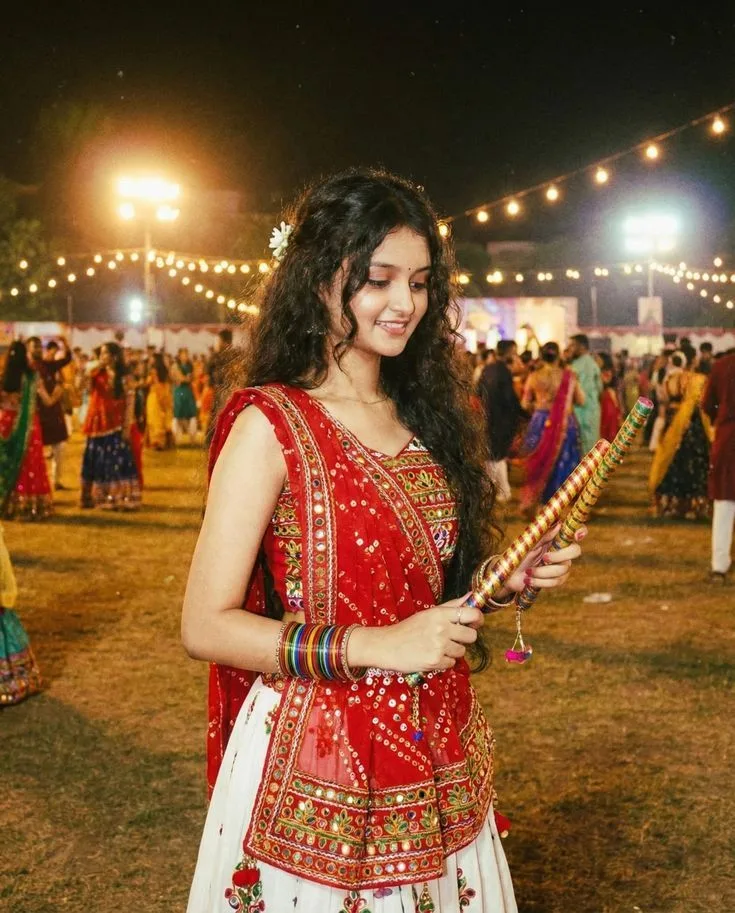 Create a photorealistic cinematic portrait of a beautiful young Indian woman enjoying a vibrant Garba night festival.
