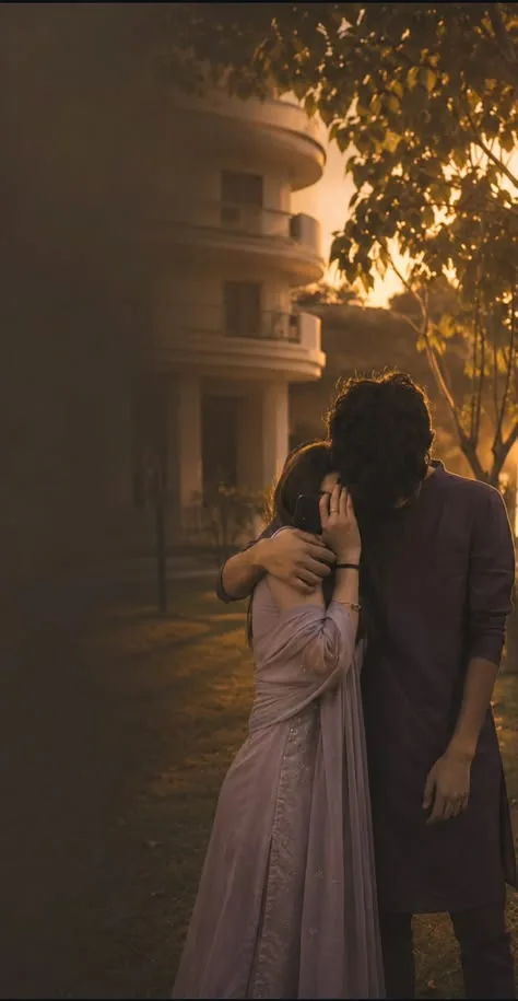 A realistic aesthetic photograph of a young South Asian couple standing outdoors during golden hour.