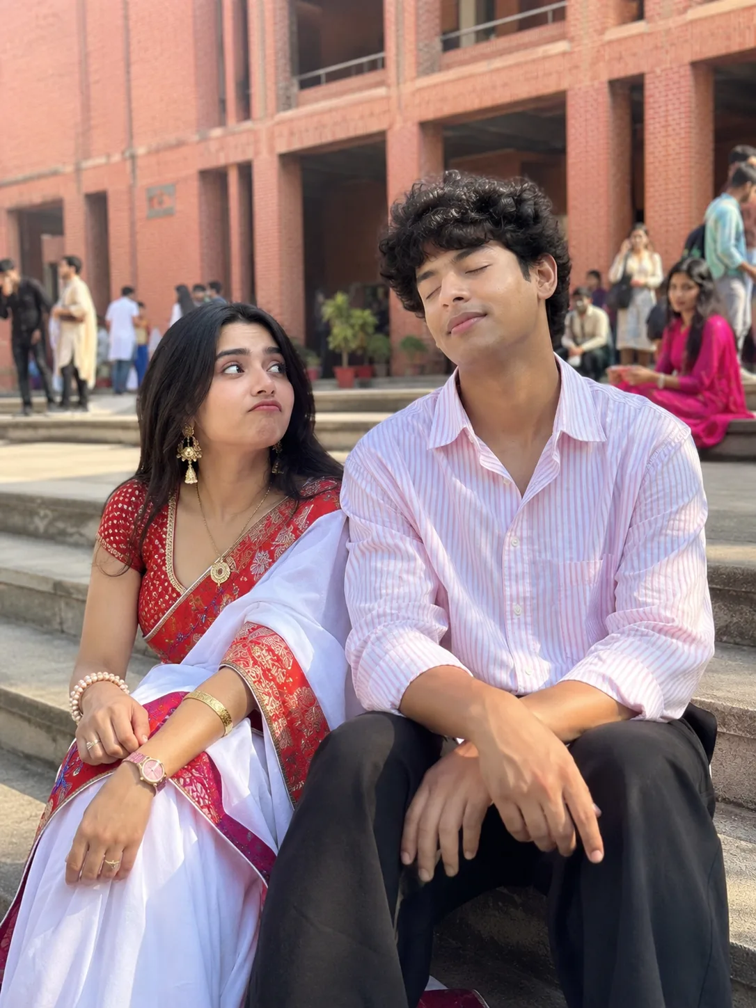 ULTRA REALSTIC CENAMATIC A CANDID, MEDIUM-SHOT PHOTOGRAPH OF A YOUNG INDIAN COUPLE SITTING CLOSE TOGETHER ON CONCRETE STEPS OUTDOORS.