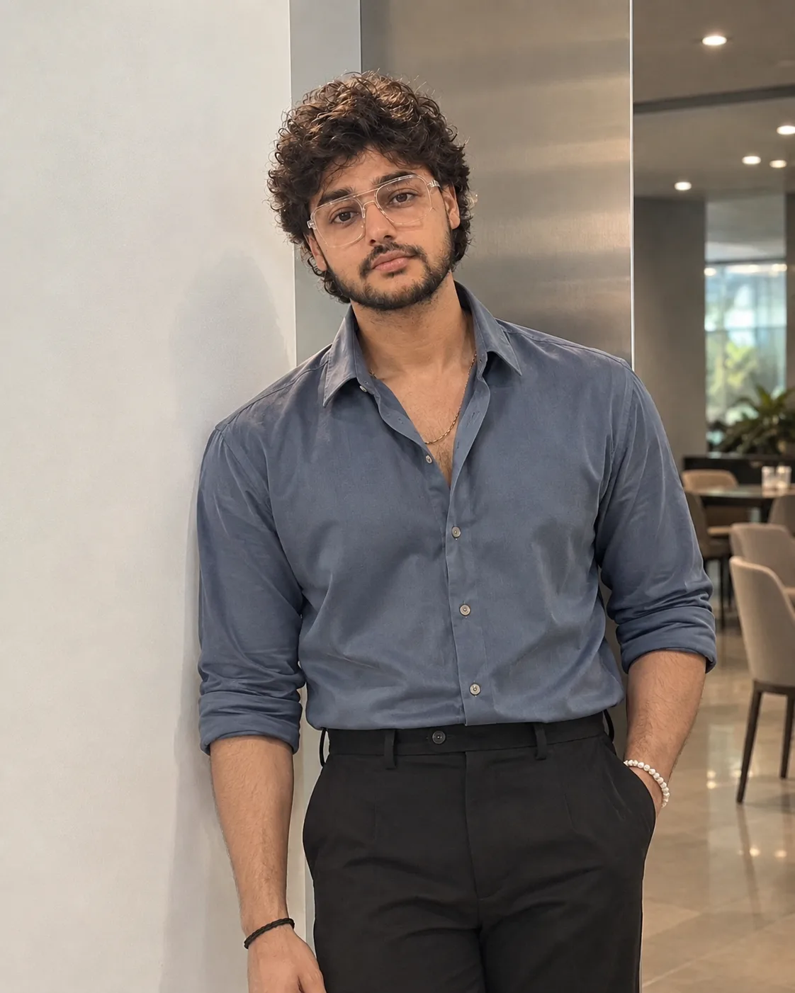 "A clean, stylish lifestyle portrait of a young man with soft, voluminous dark brown curly hair styled in a tousled, textured crop with a