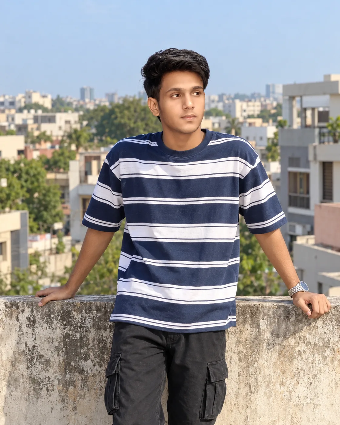 Create a highly realistic, ultra-detailed cinematic outdoor portrait photograph of a young Indian man casually posing on an elevated