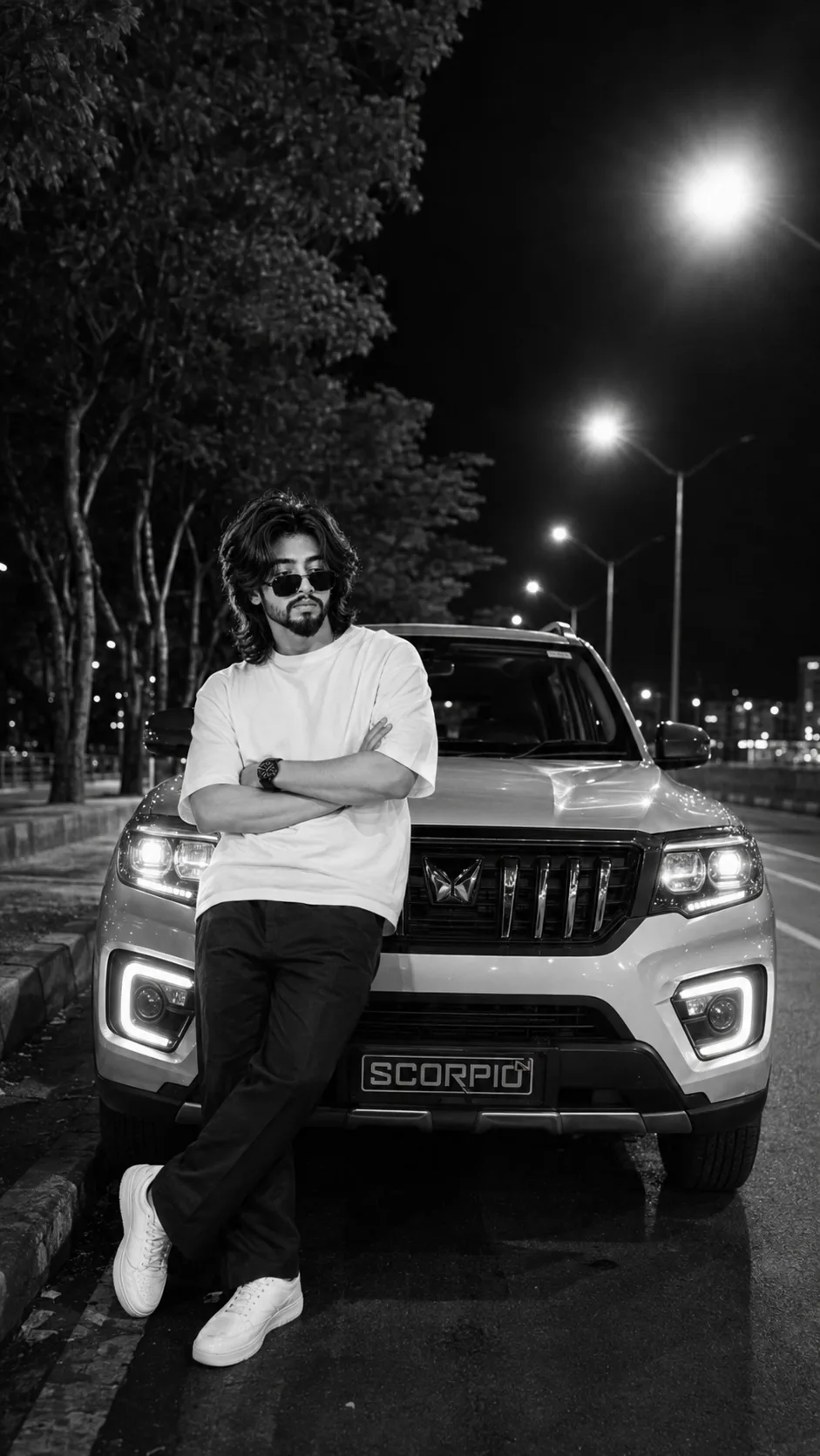 Ultra-realistic cinematic black-and-white night portrait of a stylish young Indian man leaning casually against the front of a white