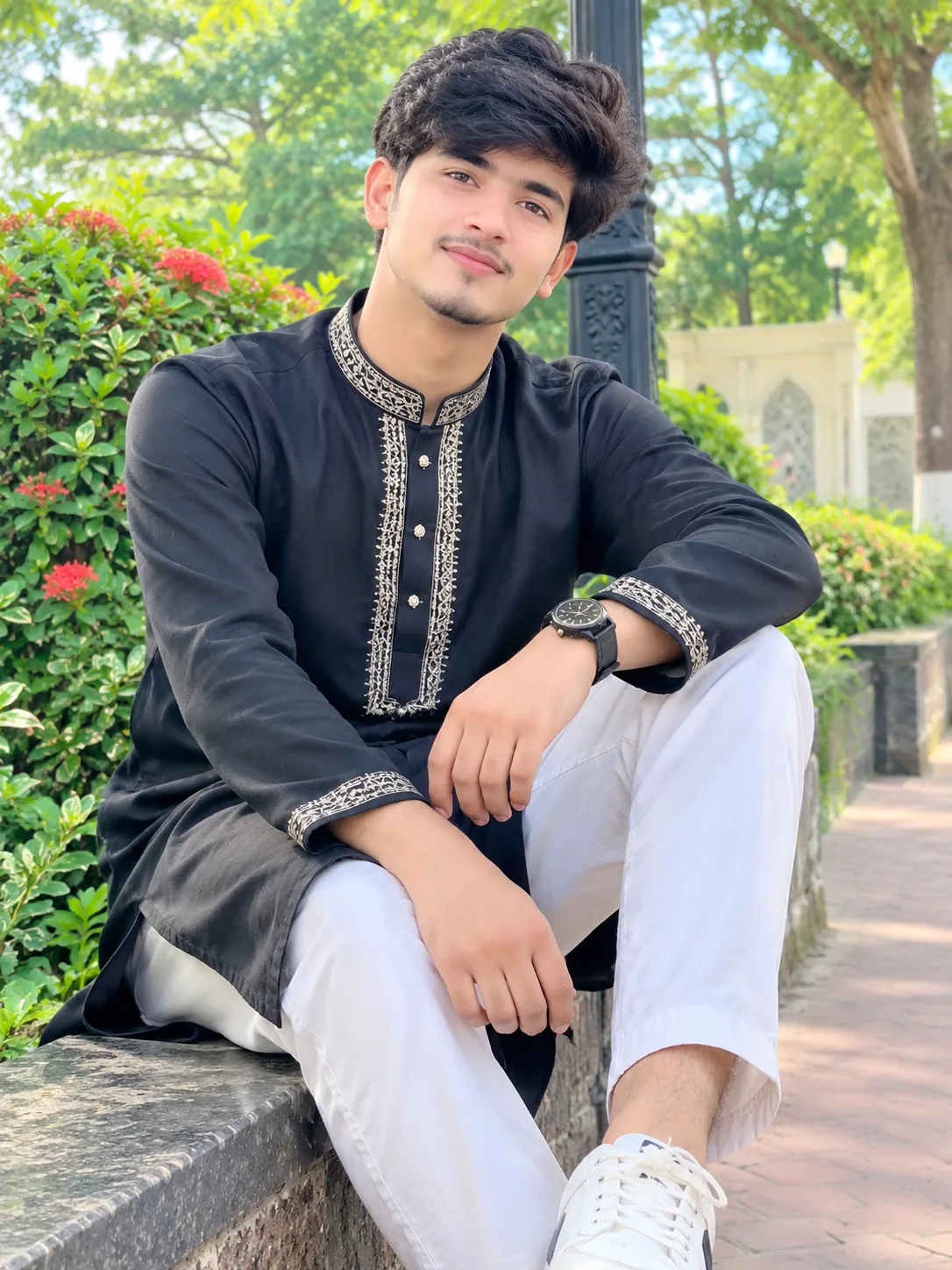 A highly realistic full-body portrait of a young South Asian man wearing a stylish black embroidered kurta with white trousers and clean