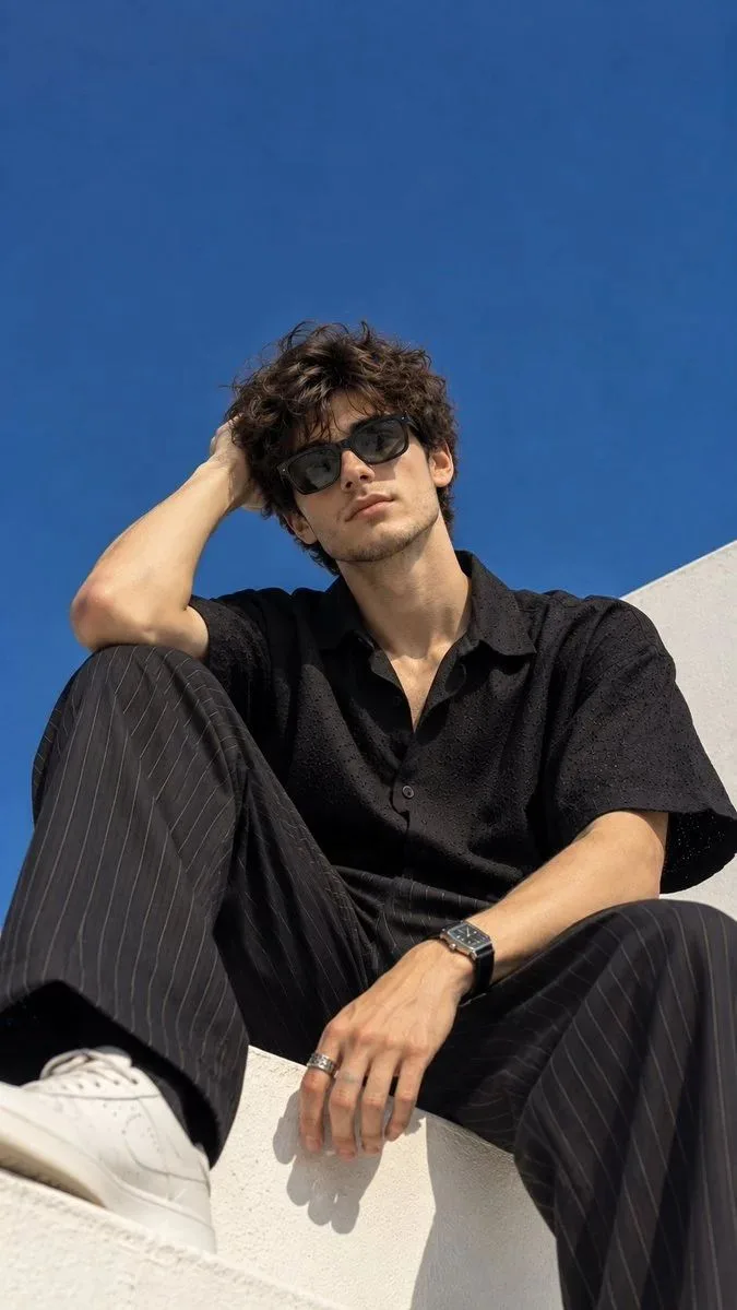 Create an ultra-realistic cinematic fashion editorial photograph of a young man captured from a dramatic low-angle perspective against a