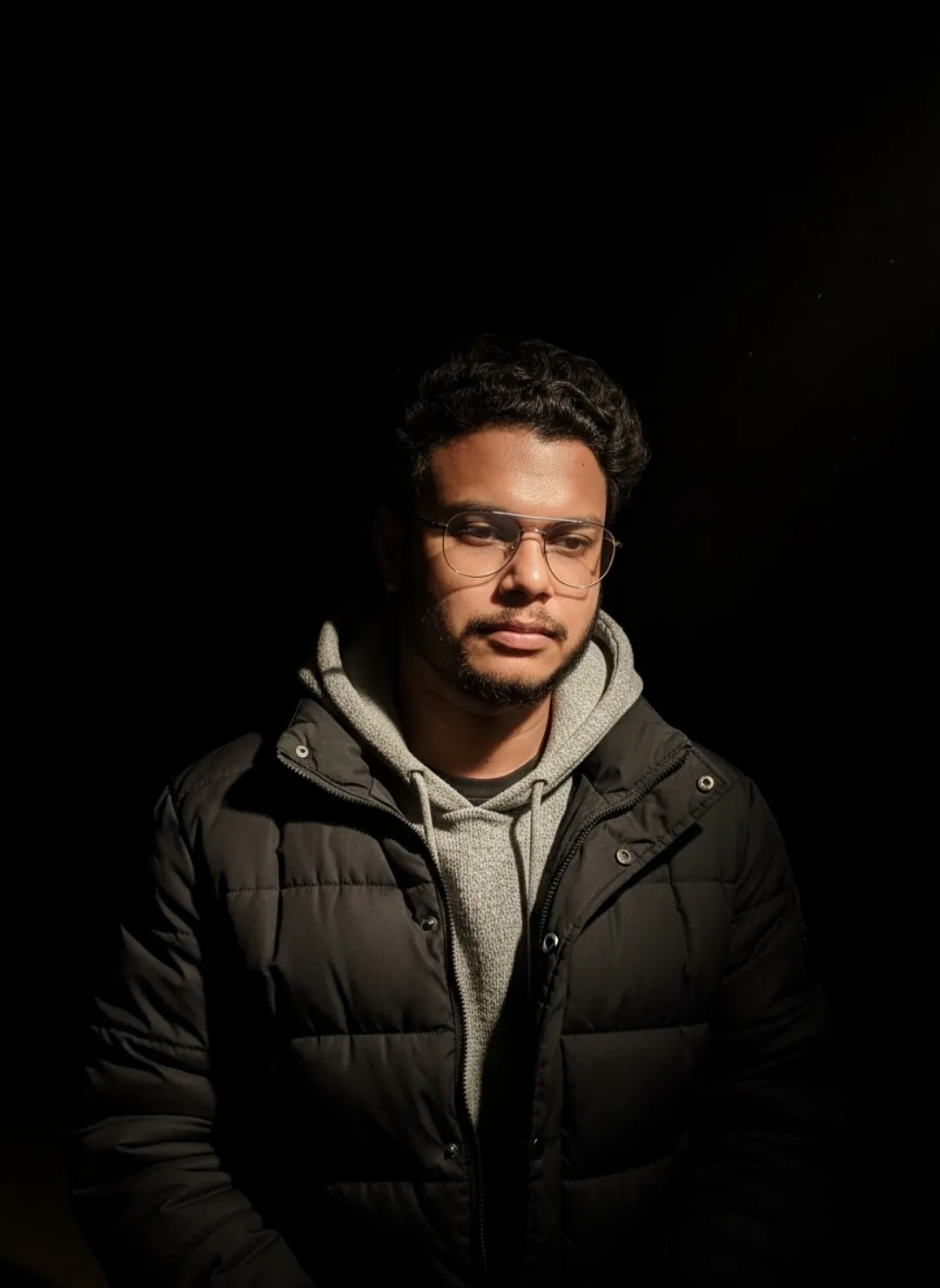 A highly detailed realistic portrait of a young South Asian man in his mid-20s with short curly black hair, light stubble beard and