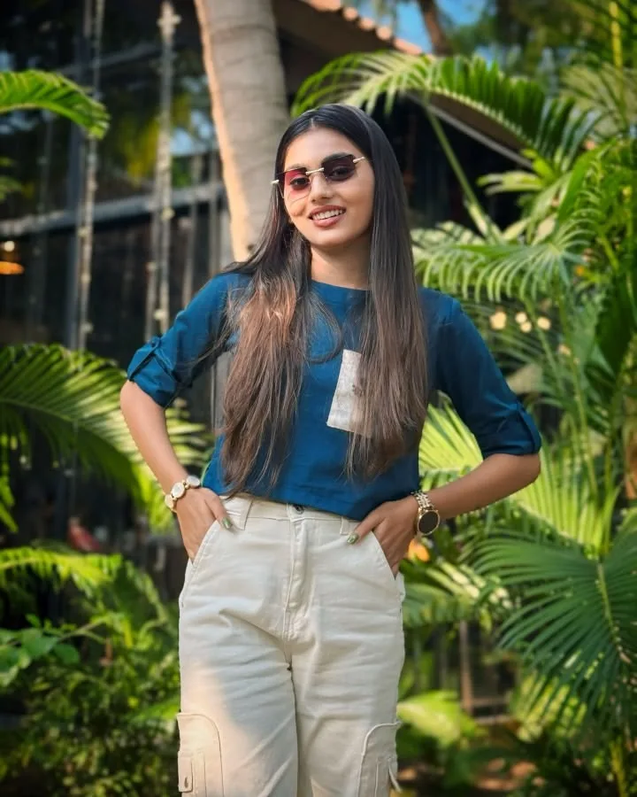 A photorealistic vertical medium shot of the young South Asian woman from the reference image, faithfully preserving her exact recognizable