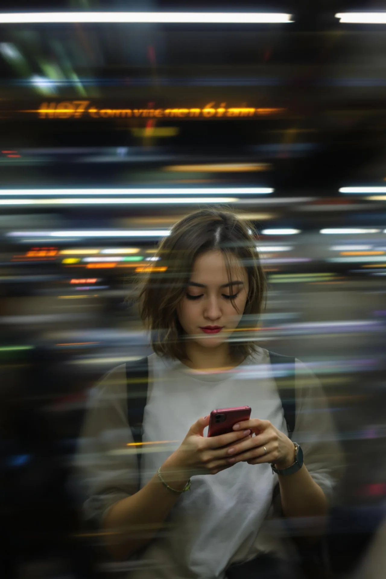 A candid, medium shot photograph of a young woman, around mid-20s, with a short, wavy brown bob haircut and a focused expression, looking