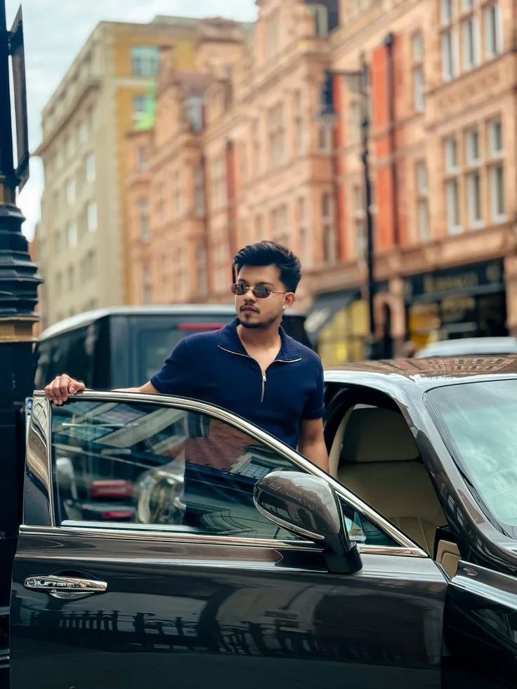 A photorealistic vertical medium shot of the young South Asian man from the reference image, faithfully preserving his exact recognizable