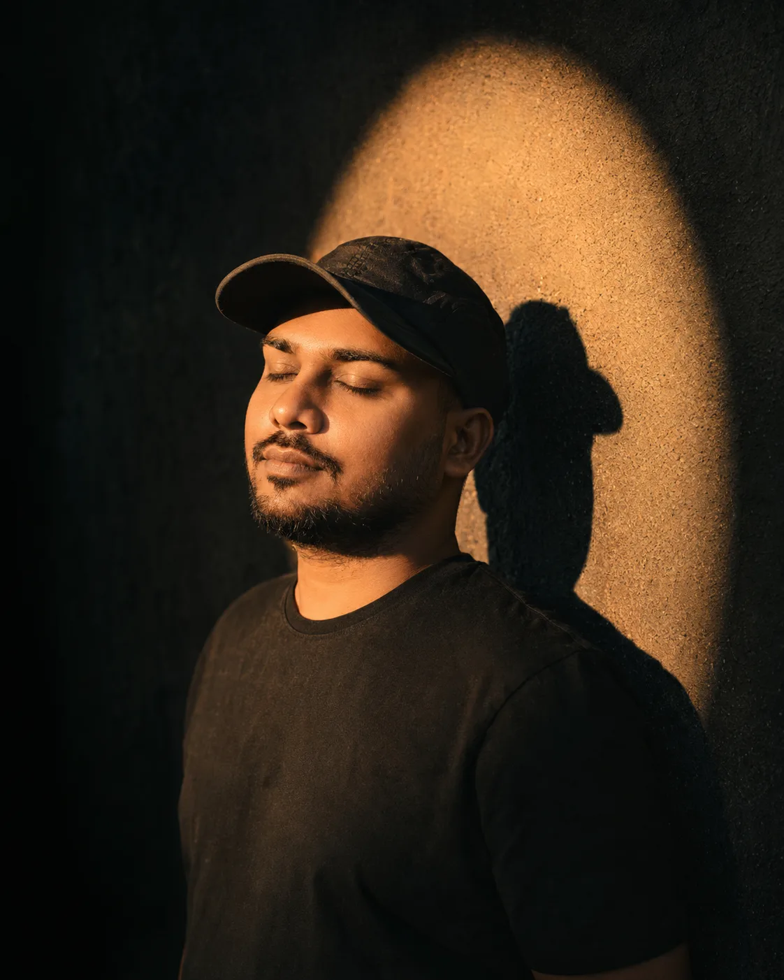 Ultra-realistic cinematic portrait of a rugged, a man leaning against a dark textured wall, head slightly tilted upward, eyes gently