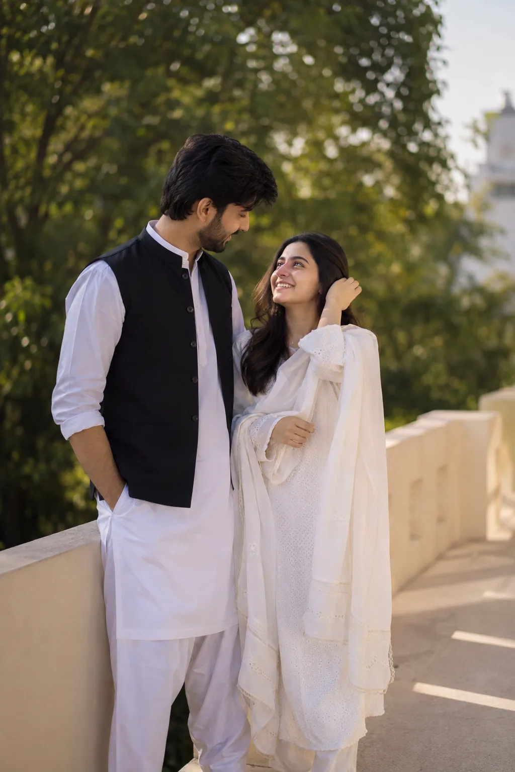 Without changing my face and hairs create a candid outdoor portrait of a young couple standing close together on a terrace balcony in soft
