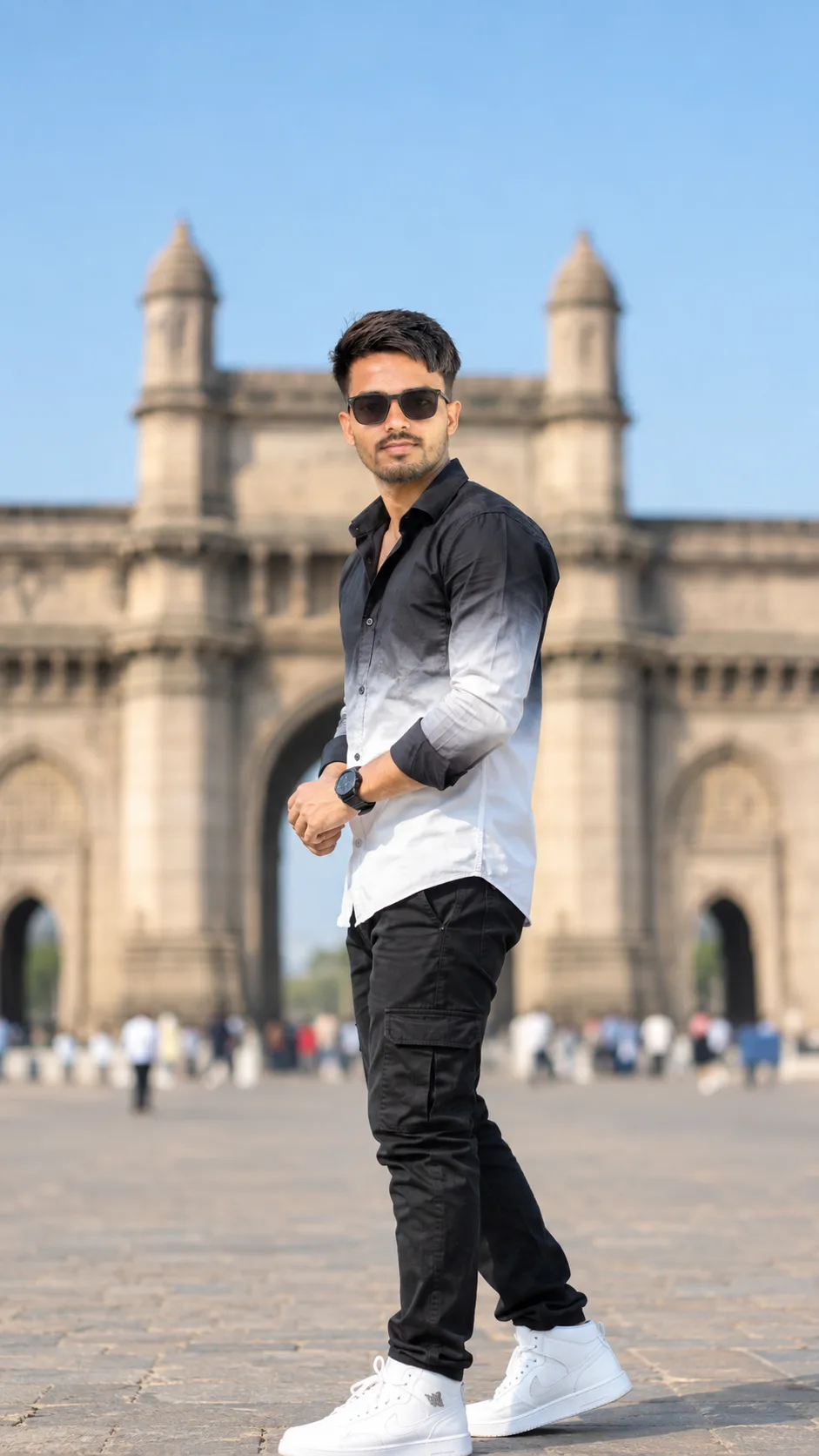 Create a photorealistic full-body fashion portrait of a stylish young South Asian man standing confidently in front of a grand historic