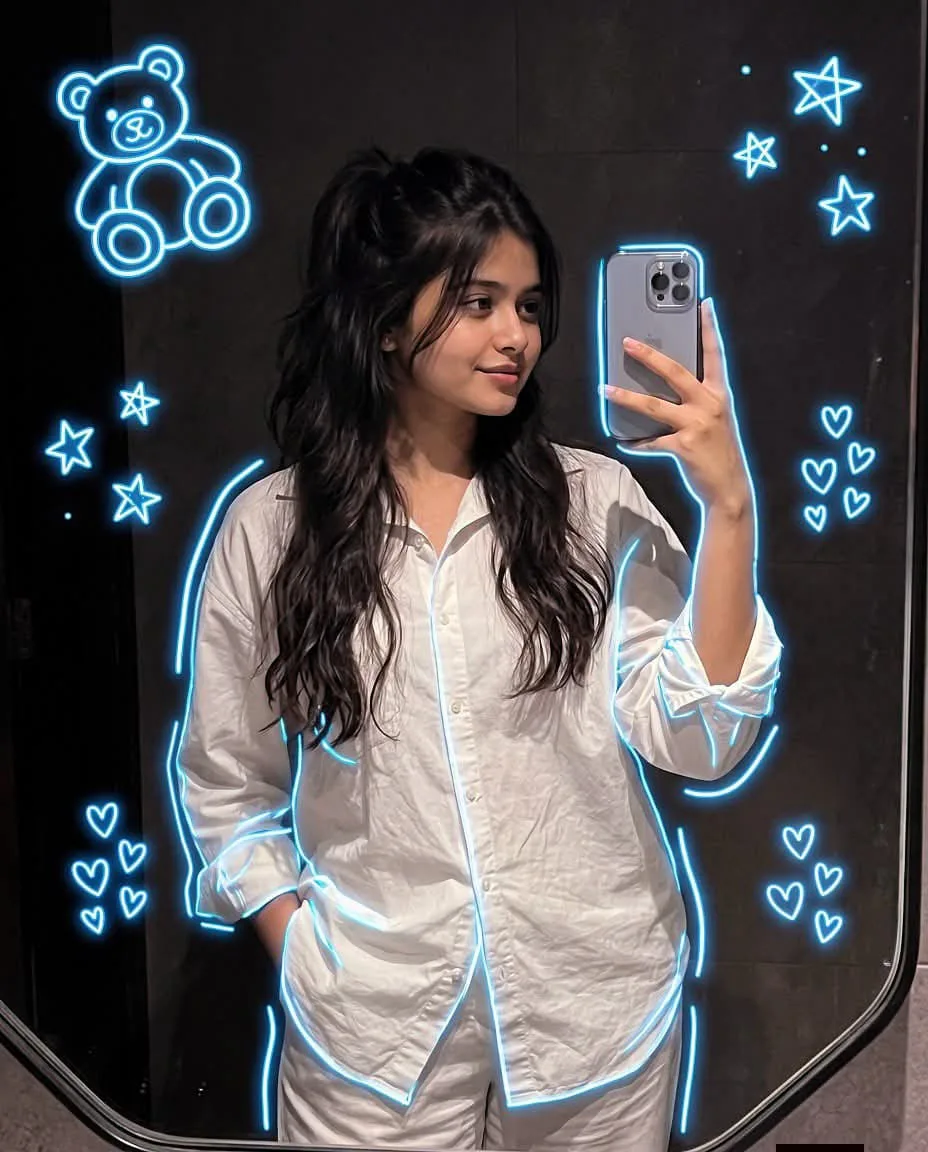A natural, amateur-quality mobile mirror selfie (mirror reflection) of a young South Asian woman (aged around 18-22) posing while looking