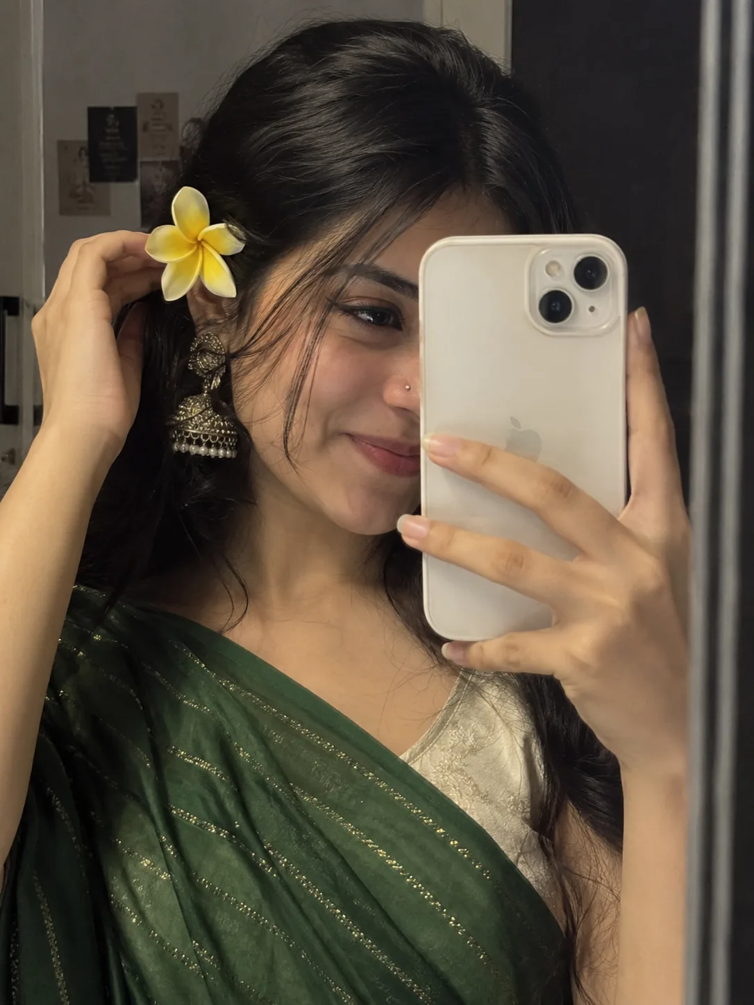 Create an image close-up mirror selfie captures a young woman dressed in traditional attire, partially obscuring her face with a white