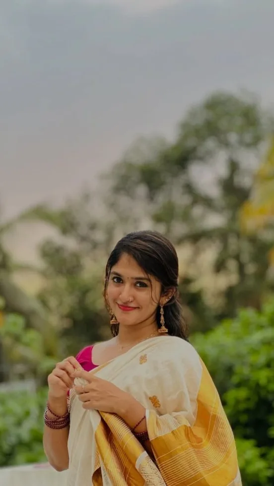 A photorealistic vertical medium shot of the young South Asian woman from the reference image, faithfully preserving her recognizable