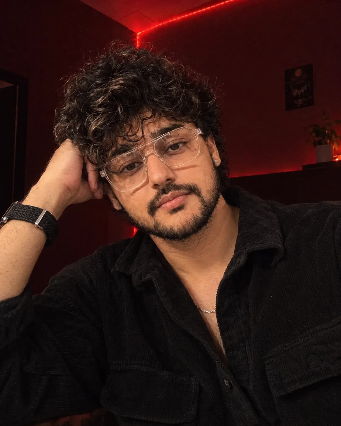 **Prompt:** "A close-up selfie-style portrait of a young man with thick, voluminous, tousled black curly hair falling across his forehead,