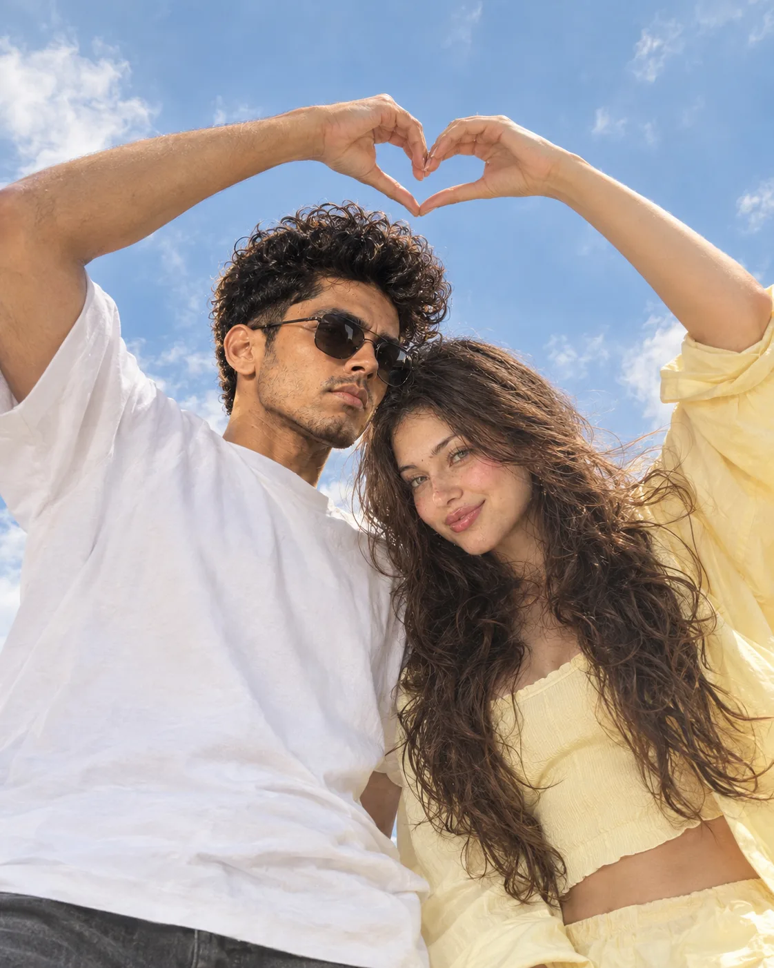 Generate a bright, aesthetic, high-resolution portrait of a reference beautiful couple shot from a extreme low angle against a clear blue