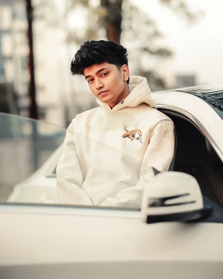 A photorealistic vertical medium shot of the young South Asian man from the reference images, faithfully preserving his exact recognizable