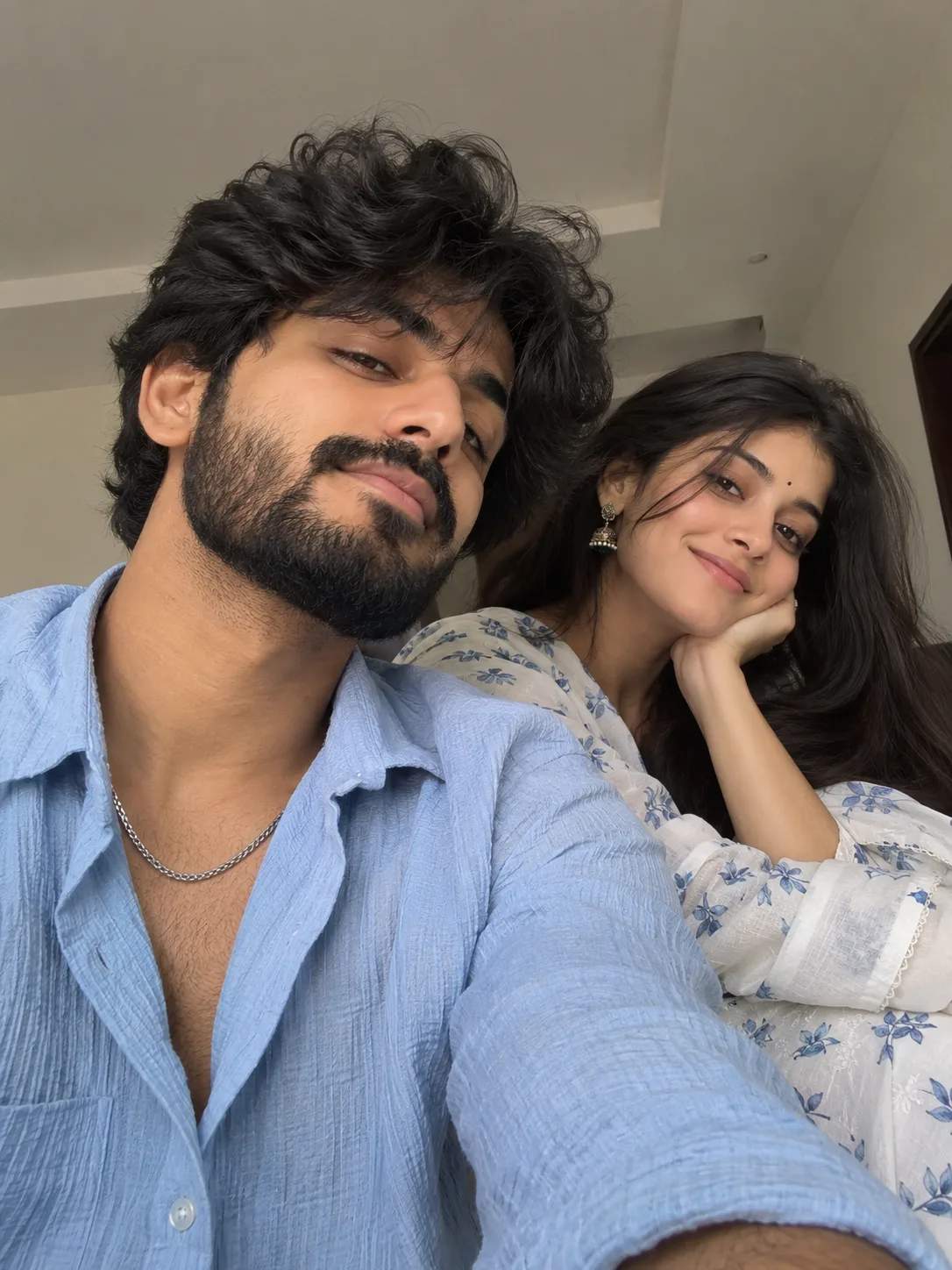Create a highly realistic candid selfie of a young South Indian couple, matching the reference image's exact composition, pose, framing and