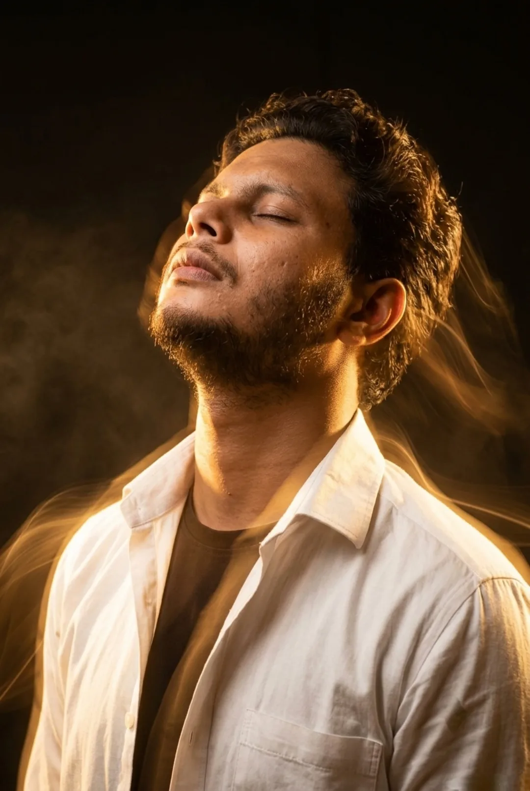 A cinematic medium close-up portrait of a 26-year-old Indian man with short dark curly hair and a well-groomed beard, looking upward with a