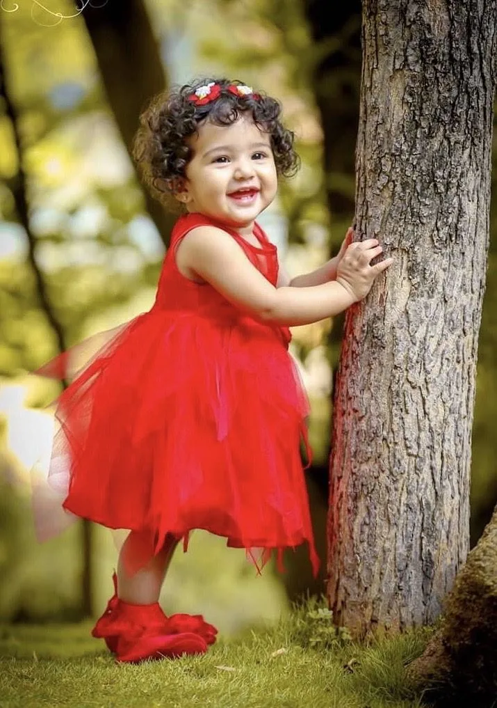 A photorealistic medium-full shot capturing the exact joyful expression, facial features, and adorable curly dark hair of the young girl