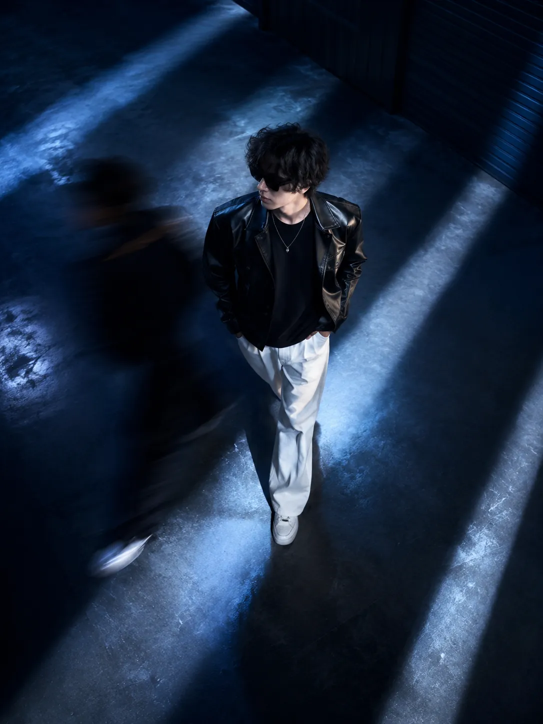 Using the uploaded image as the subject reference, recreate the subject in a glossy black leather jacket, black t-shirt, white wide-leg