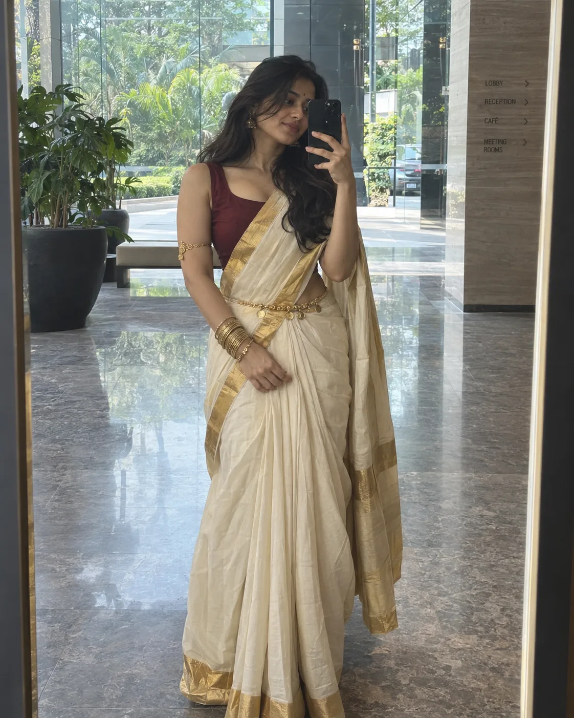 A high-resolution full-length mirror selfie of a young woman in a modern glass-walled lobby.