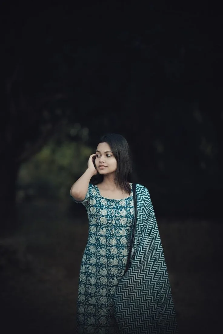 A photorealistic vertical medium shot of the young South Asian woman from the reference image, faithfully preserving her recognizable