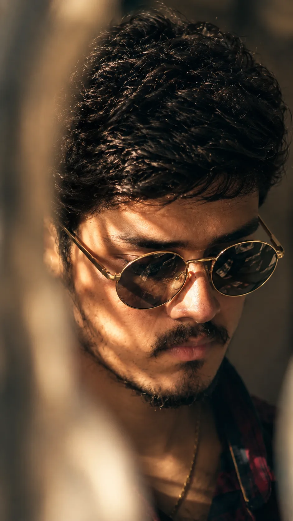 Create an ultra-realistic cinematic close-up portrait of a young South Asian man with thick, naturally wavy black hair, a well-defined