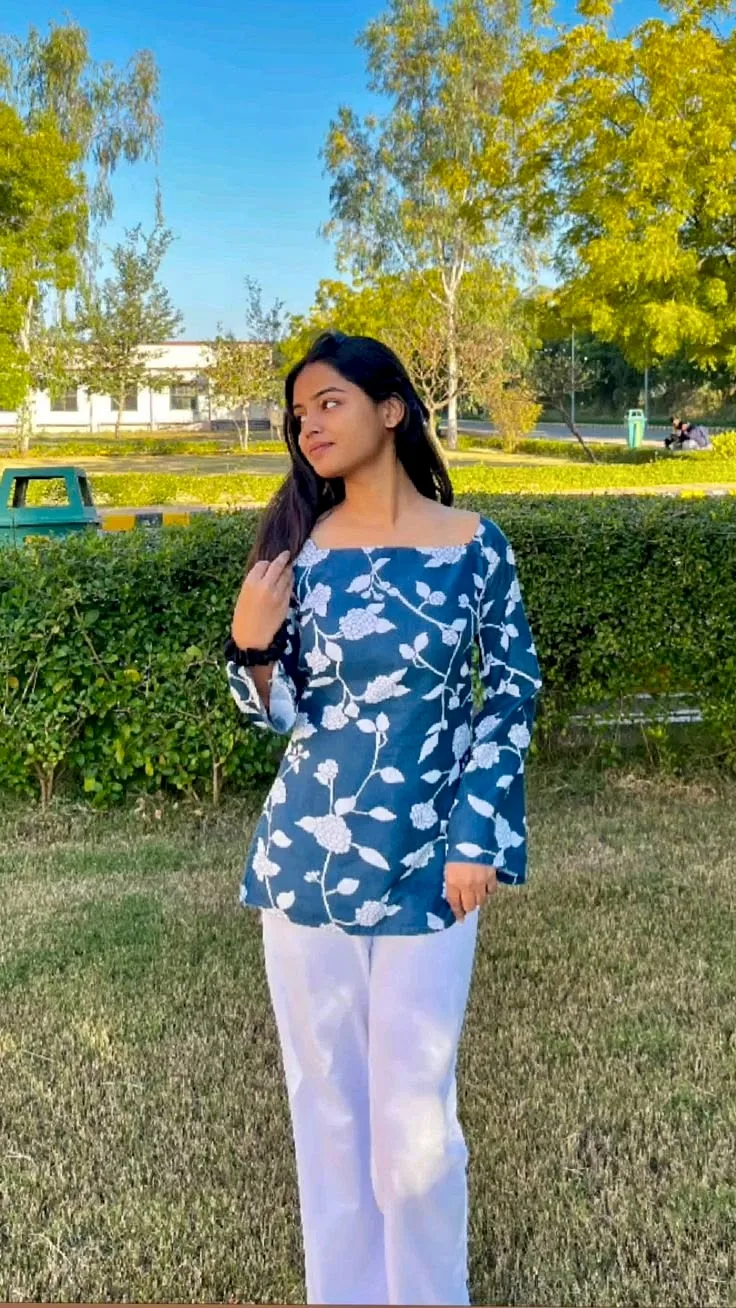 A photorealistic vertical medium-full portrait of the young South Asian woman from the reference image, faithfully preserving her exact