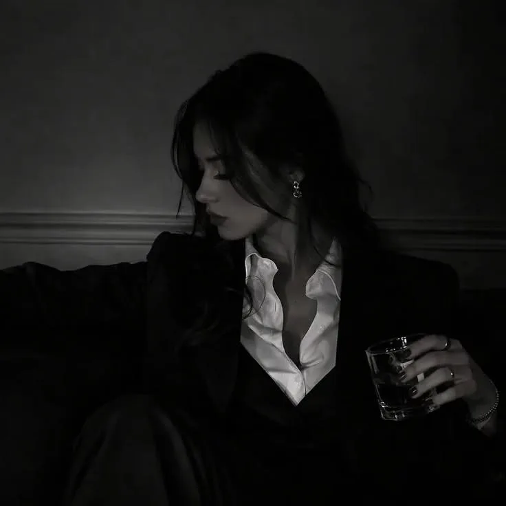 Create an ultra-photorealistic cinematic black-and-white portrait photograph of a fictional young adult woman sitting casually in an
