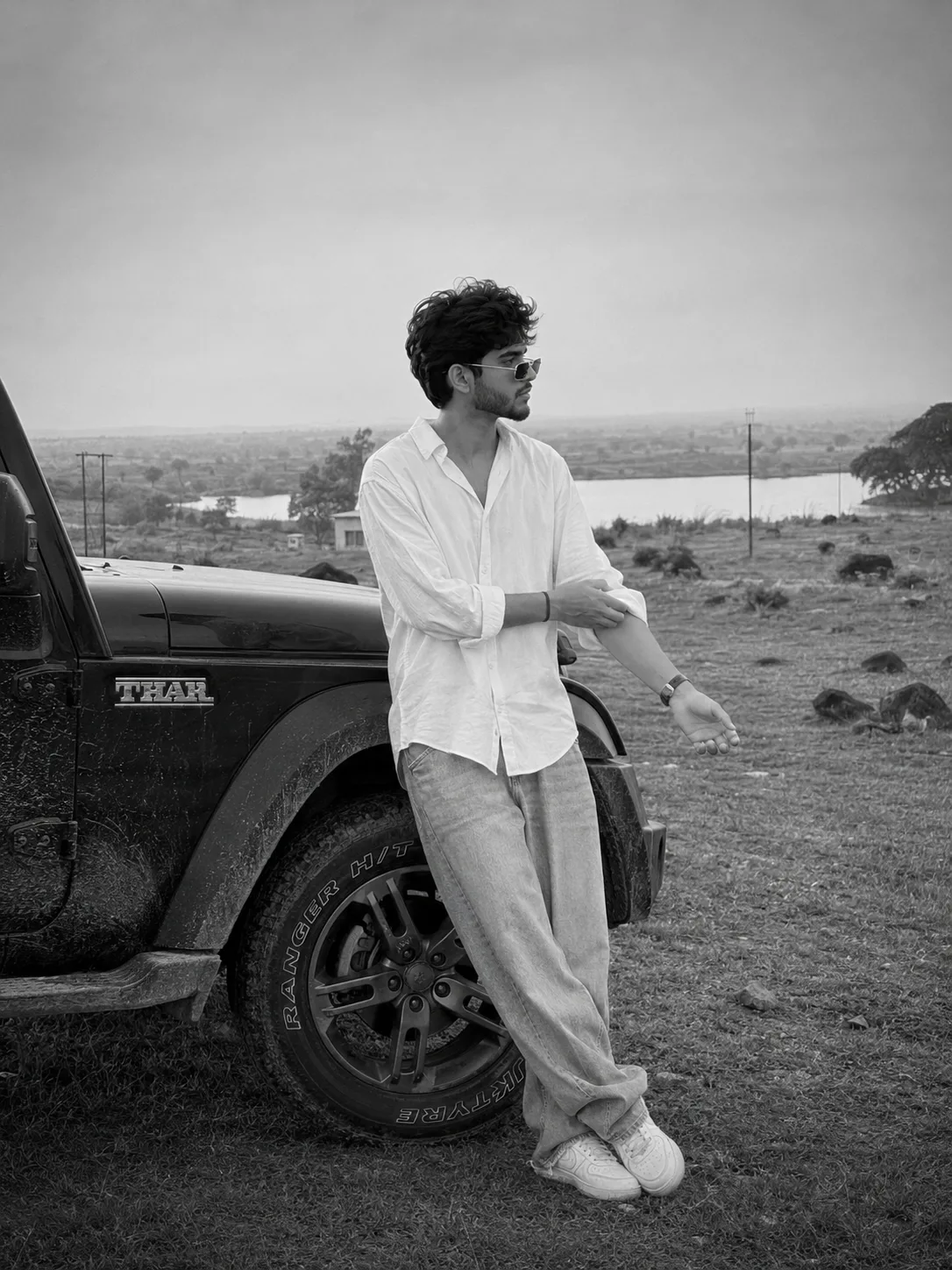 Black and white analog film photograph, photorealistic, ultra detailed, cinematic moody aesthetic, a young South Asian man in his mid-20s