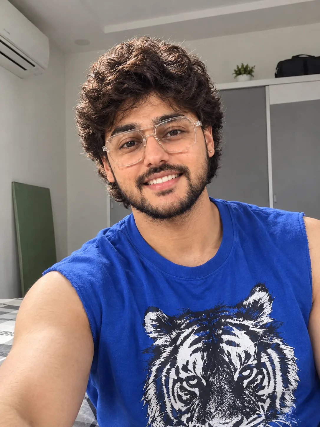 "A bright, casual selfie-style portrait of a young man with thick, wavy dark brown hair and a full, neatly groomed black beard and