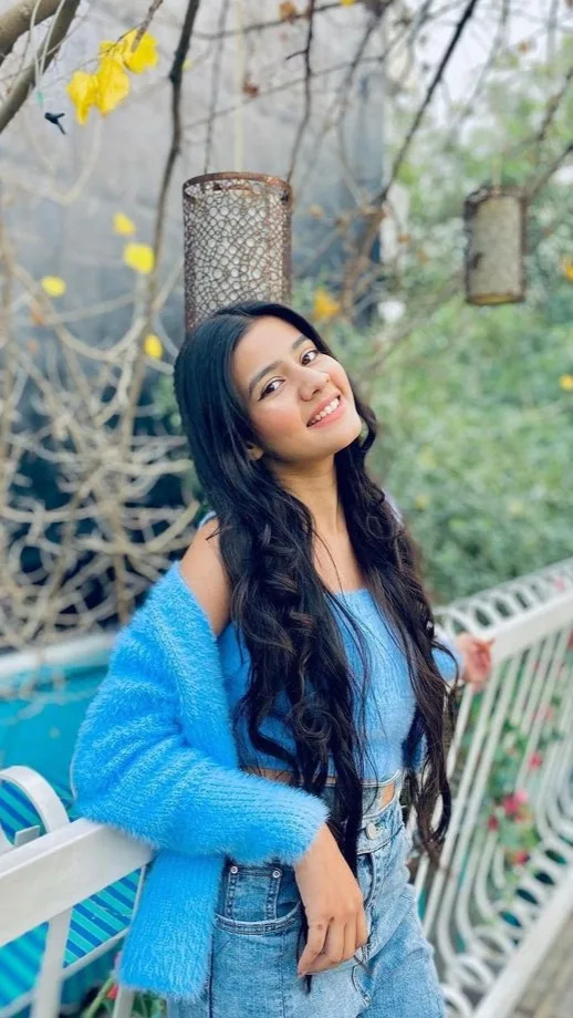 A photorealistic vertical medium shot of the young South Asian woman from the reference image, faithfully preserving her exact recognizable