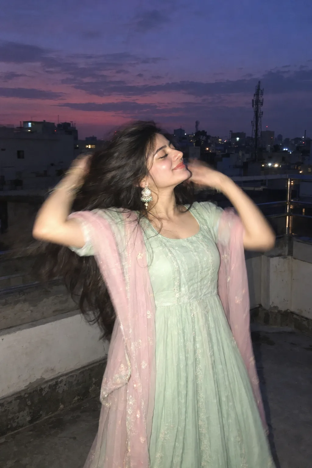 Create an ultra-realistic candid rooftop portrait of a woman(the reference Image given) during blue hour, just after sunset, with a dusky