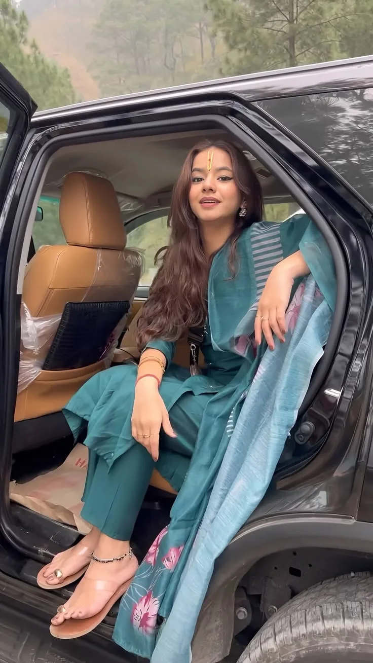Create a **photorealistic vertical lifestyle portrait** of a young South Asian woman sitting gracefully in the open rear door of a premium