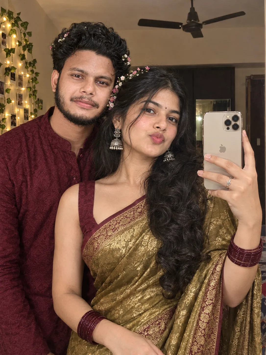 A young Indian couple taking a mirror selfie indoors.
