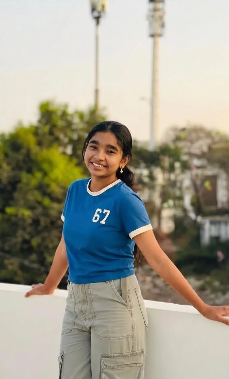 A photorealistic vertical medium shot of the young South Asian woman from the reference images, faithfully preserving her exact