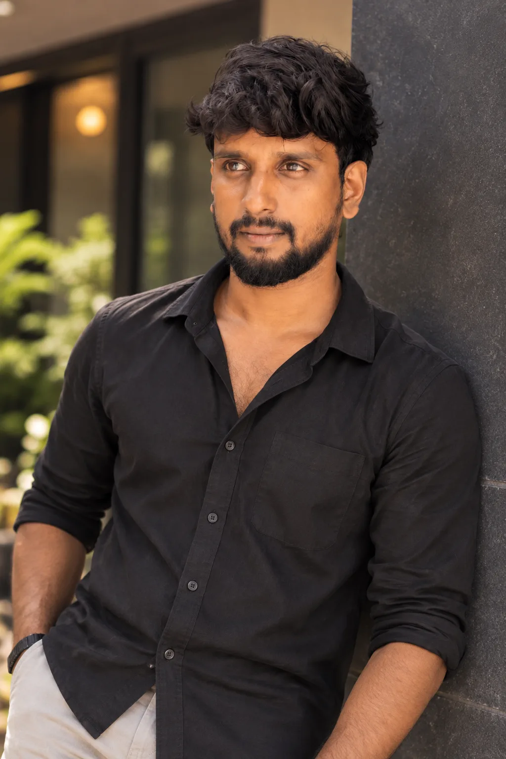 Create a cinematic, vertical portrait of the same adult South Asian man from the reference image, captured in warm natural light as he