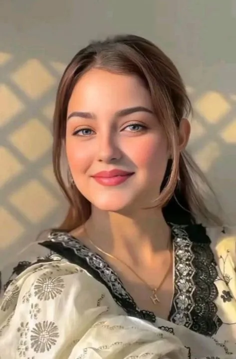 A beautiful close-up 3:4 portrait of a gorgeous young South Asian woman with striking light grey-blue eyes and a warm, gentle smile.